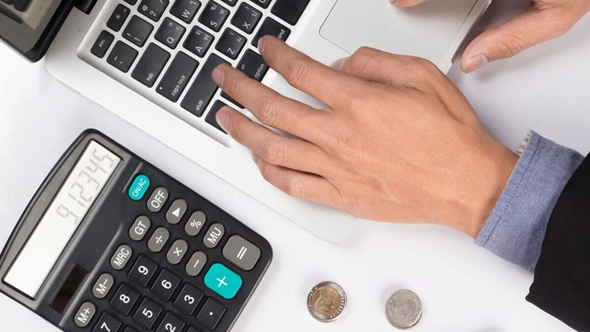 calculadora y mano escribiendo en un ordenador