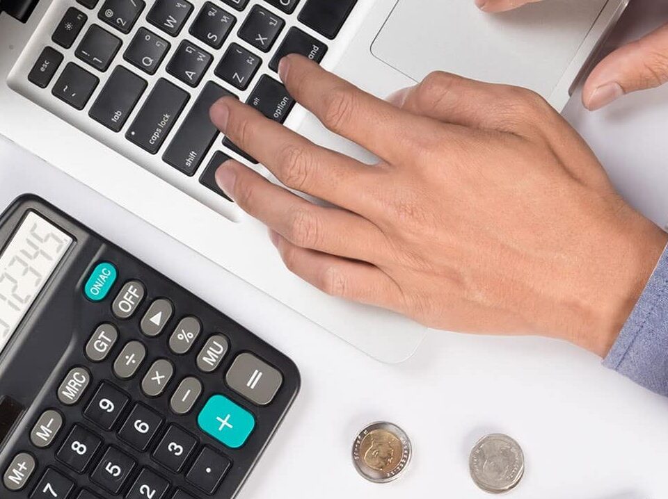 calculadora y mano escribiendo en un ordenador